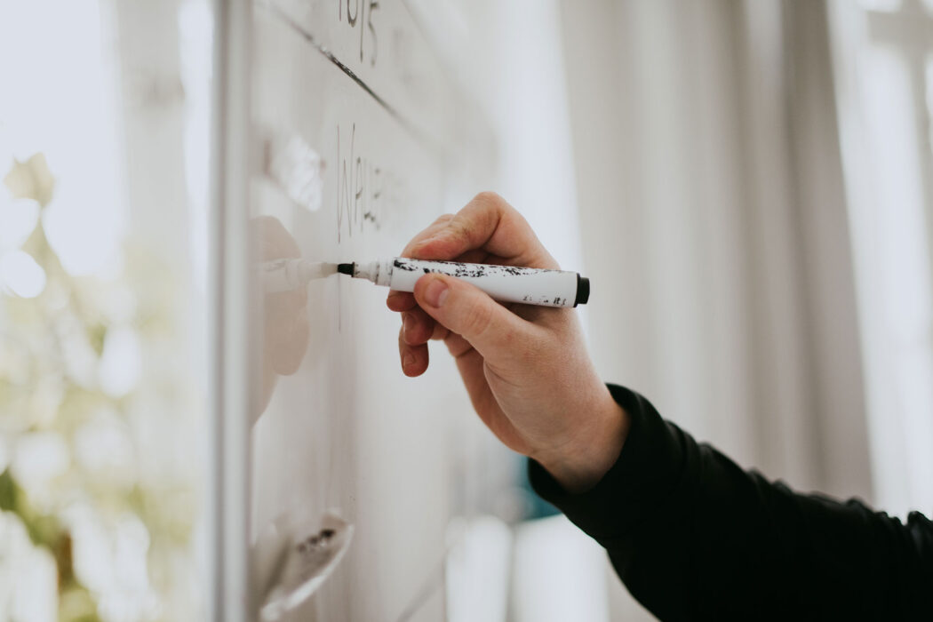 Hand som skriver på en whiteboardtavla